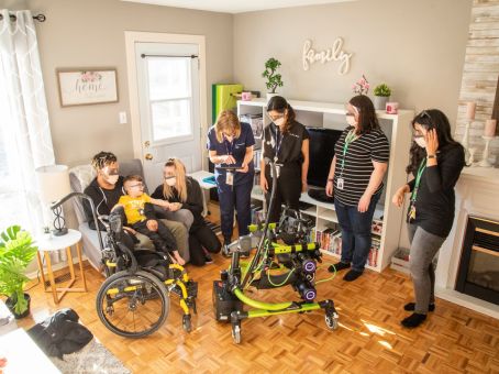 A patient with two adults and four healthcare team members in a room with the robot walker