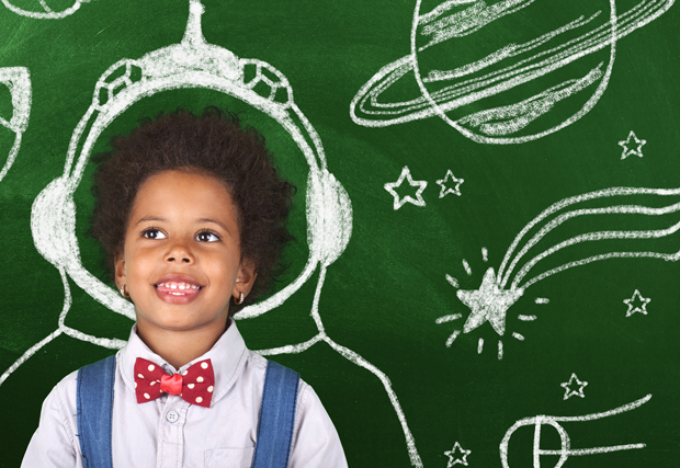 a kid in front of a chalkboard with rockets and planets drawn on it